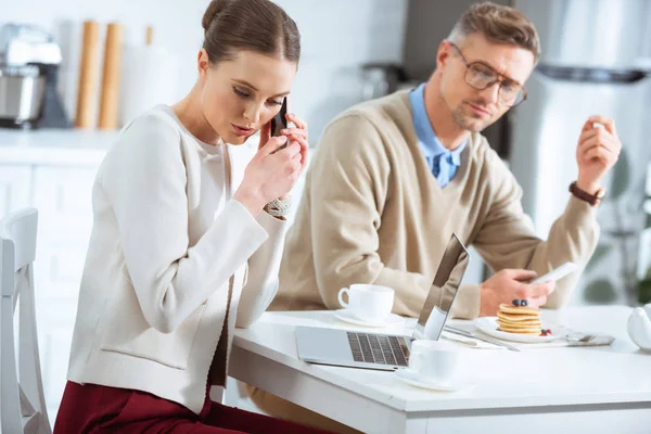 Man looking at woman secretly talking on smartphone during breakfast — Stock Photo