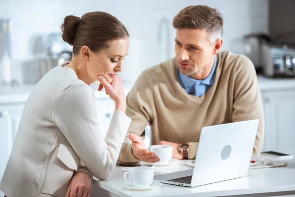 Adult couple using laptop and having conversation during breakfast in morning — Stock Photo