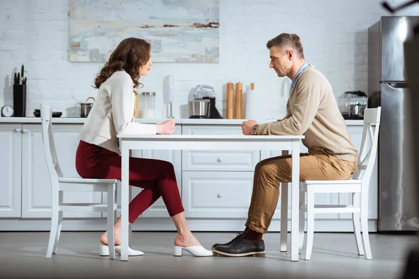 Недовольная пара, сидящая с сжатыми кулаками за столом на кухне — стоковое фото