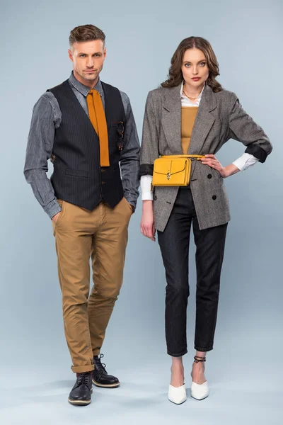 Schönes stylisches Paar in formaler Kleidung, das in die Kamera schaut, während es auf grauem Hintergrund posiert — Stockfoto