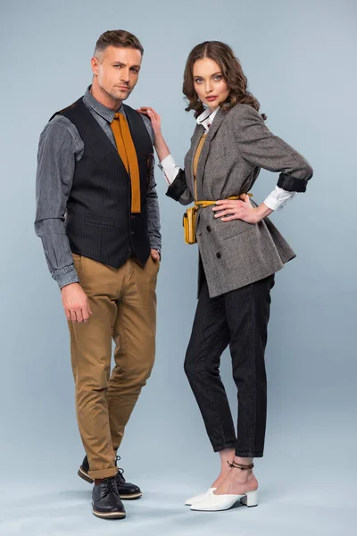 Beau couple élégant en tenue formelle regardant la caméra tout en posant sur fond gris — Photo de stock