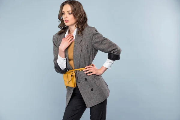 Schöne stilvolle Frau in formaler Kleidung mit der Hand auf der Hüfte posiert isoliert auf grau — Stockfoto