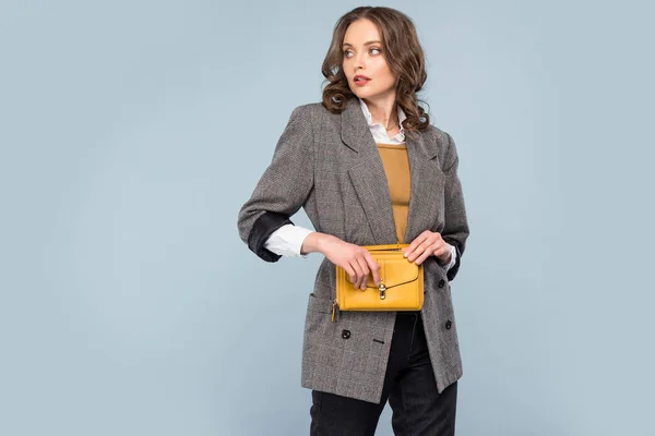 Hermosa mujer con estilo en bolsa de sujeción de desgaste formal y posando aislado en gris con espacio de copia - foto de stock