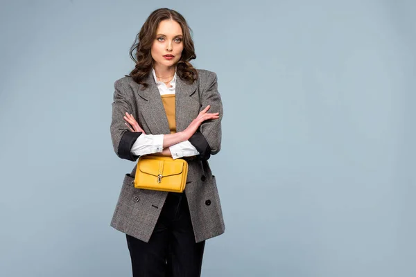 Beautiful stylish woman in formal wear with arms crossed posing isolated on grey with copy space — Stock Photo