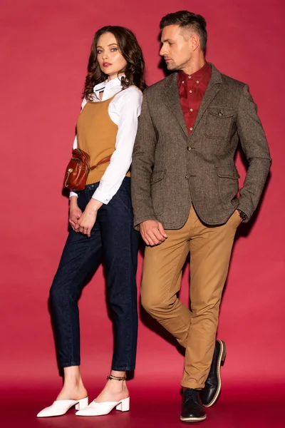 Atractiva pareja de moda en ropa formal posando sobre fondo rojo — Stock Photo