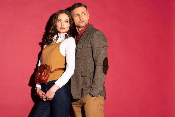 Beautiful fashionable couple in formal wear posing on red background with copy space — Stock Photo