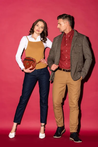 Belo casal elegante em desgaste formal posando no fundo vermelho — Fotografia de Stock