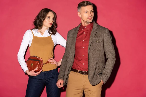 Beautiful stylish couple in formal wear posing on red background — Stock Photo