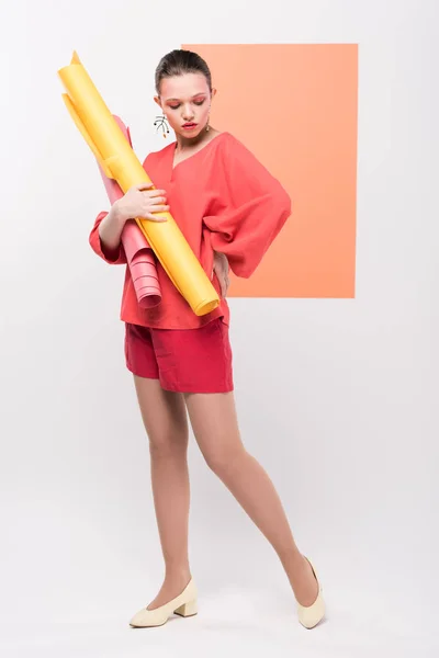 Bela menina da moda segurando rolos de papel e posando com coral vivo no fundo — Fotografia de Stock