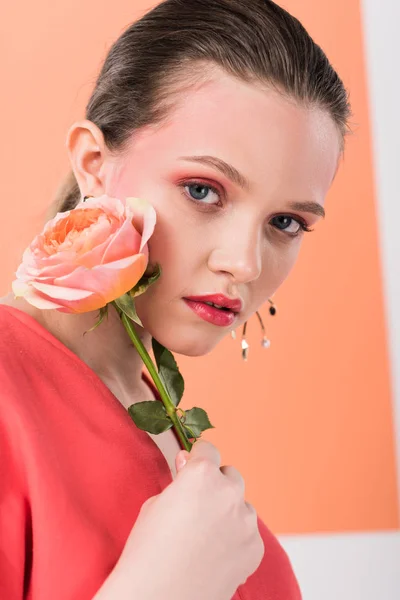 Beautiful stylish girl holding rose, looking at camera and posing with living coral on background — Stock Photo