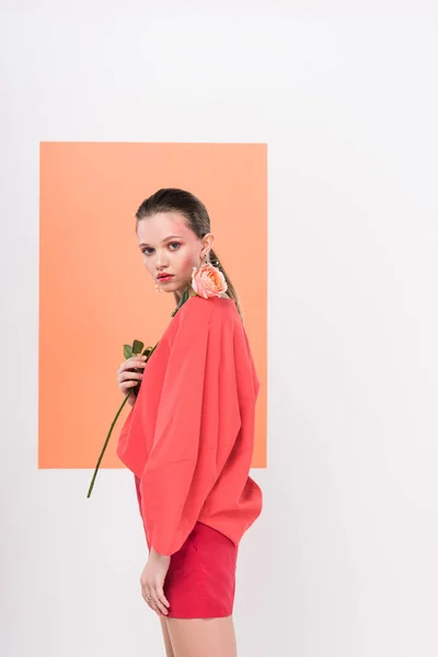 Beautiful stylish girl looking at camera, holding rose and posing with living coral on background — Stock Photo