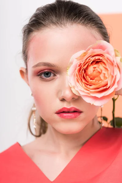 Beautiful stylish girl holding rose, looking at camera and posing with living coral on background — Stock Photo