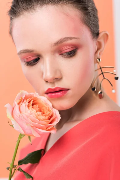 Foco seletivo de menina elegante bonita segurando rosa e posando com coral vivo no fundo — Fotografia de Stock