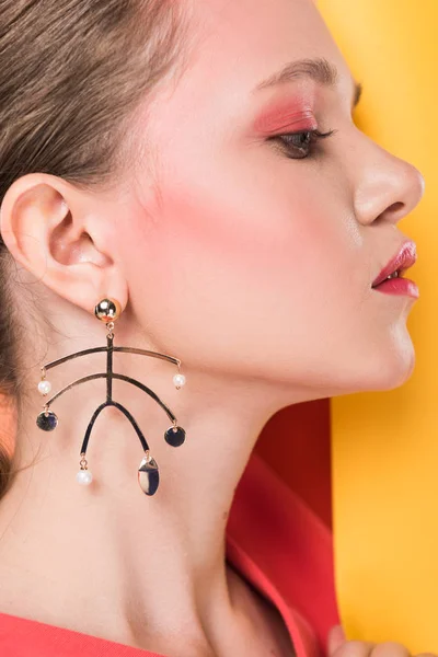 Vista laterale di bella ragazza alla moda con orecchino in possesso di carta ribalta — Foto stock