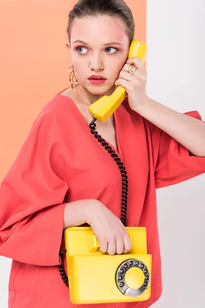 Beautiful stylish girl talking on retro telephone and posing with living coral on background — Stock Photo