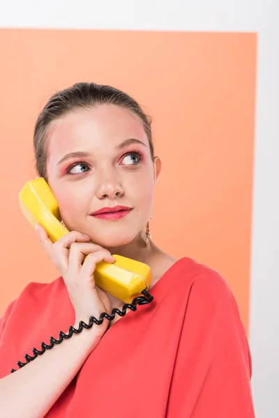 Selective focus of beautiful stylish girl holding retro telephone and posing with living coral on background — Stock Photo