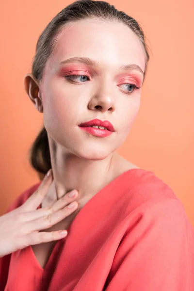 Portrait of beautiful stylish girl touching neck and posing isolated on living coral — Stock Photo