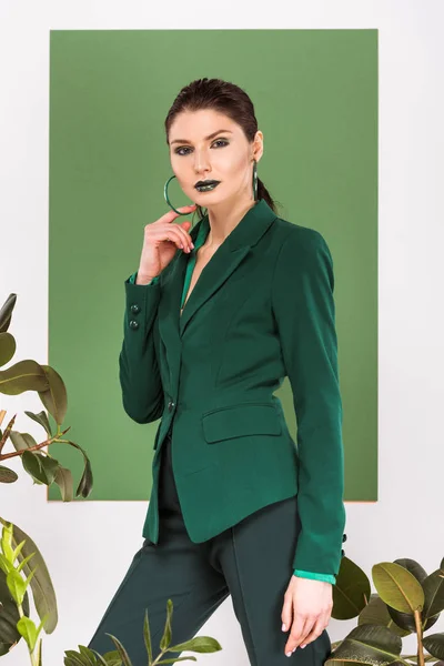 Hermosa mujer con estilo mirando a la cámara y posando con plantas y verde mar en el fondo - foto de stock