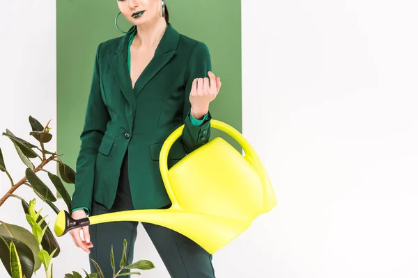 Vista recortada de la mujer elegante sosteniendo regadera y posando con verde marino en el fondo - foto de stock