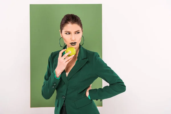 Beautiful stylish woman holding apple and posing with sea green on background — Stock Photo