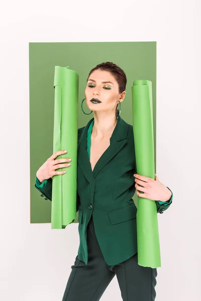 Hermosa mujer elegante sosteniendo rollos de papel y posando con verde marino en el fondo - foto de stock