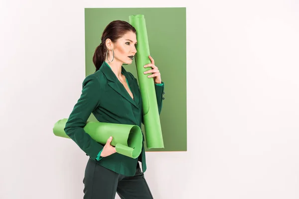 Hermosa mujer elegante sosteniendo rollos de papel, mirando hacia otro lado y posando con verde marino en el fondo - foto de stock