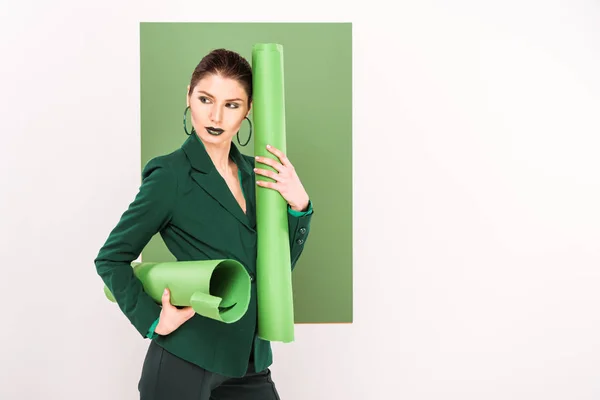 Beautiful stylish woman holding paper rolls, looking away and posing with sea green on background — Stock Photo