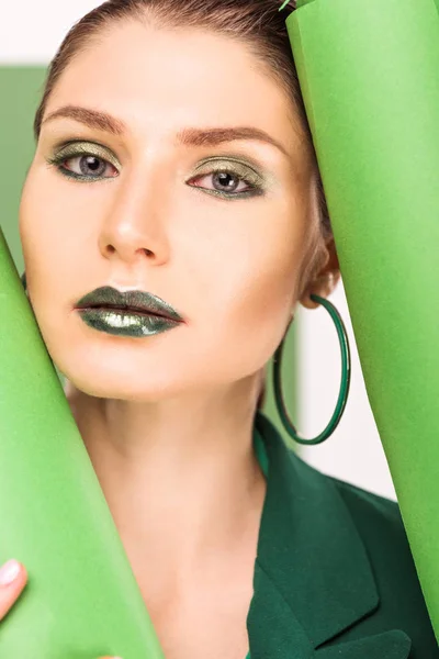 Красива стильна жінка дивиться на камеру і позує з морськими зеленими паперовими рулонами — стокове фото