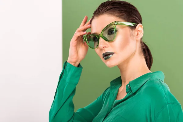 Belle femme à la mode dans les lunettes de soleil posant et regardant loin avec le vert de la mer sur le fond — Photo de stock