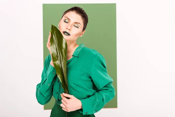 Schöne stilvolle Frau hält Blatt und posiert mit Meeresgrün auf dem Hintergrund — Stockfoto