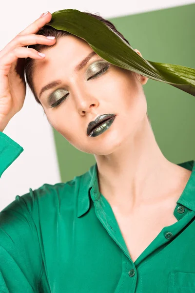 Портрет красивой стильной женщины, держащей лист и позирующей с зеленым на заднем плане — стоковое фото