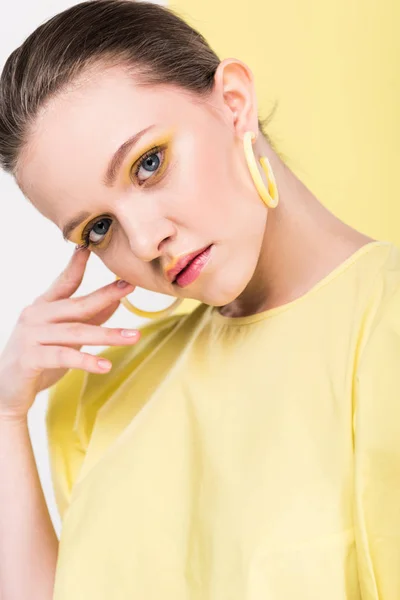 Portrait of beautiful stylish girl touching face and looking at camera with limelight on background — Stock Photo