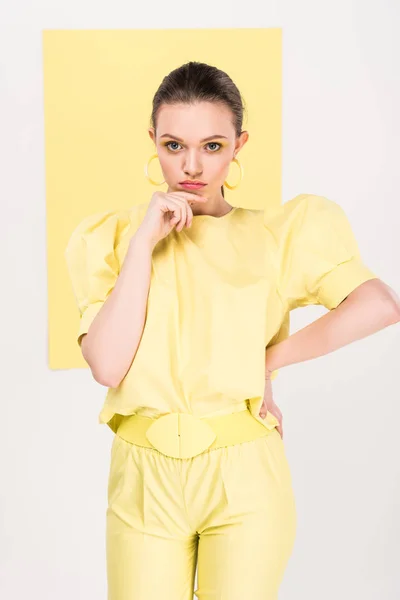 Beautiful stylish girl touching chin and posing with limelight on background — Stock Photo