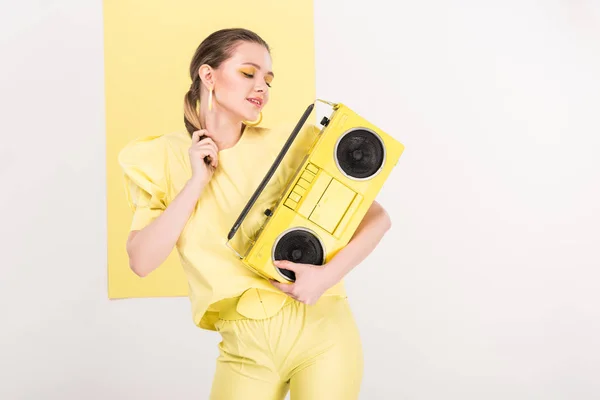 Beautiful stylish girl holding retro boombox and posing with limelight on background — Stock Photo