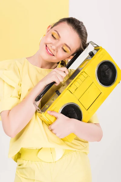 Fille élégante tenant boombox rétro et posant avec la lumière sur le fond — Photo de stock