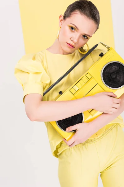 Beautiful stylish girl holding retro boombox and posing with limelight on background — Stock Photo