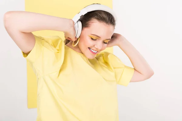 Beautiful stylish girl in headphones listening music with limelight on background — Stock Photo