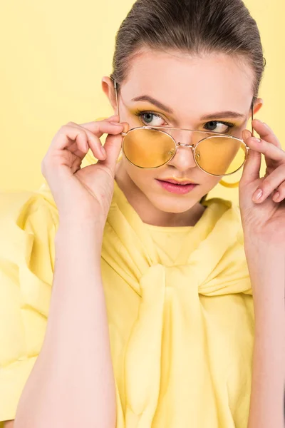 Belle fille à la mode tenant des lunettes de soleil et posant isolé sous les feux de la rampe — Photo de stock