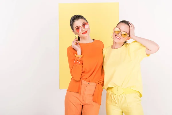 Beautiful fashionable girls in sunglasses posing with limelight on background — Stock Photo