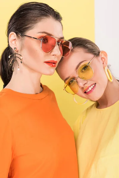Selective focus of beautiful stylish girls in sunglasses posing with limelight on background — Stock Photo
