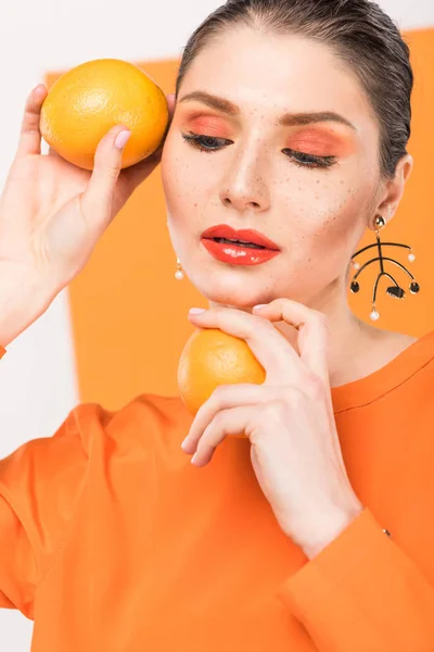 Bela mulher elegante segurando laranjas e posando com açafrão no fundo — Fotografia de Stock