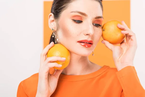 Belle femme élégante tenant des oranges et posant avec curcuma sur fond — Photo de stock