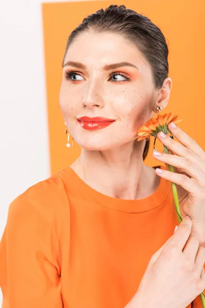 Bella elegante giovane donna che tiene fiore e posa con tumerico su sfondo — Foto stock