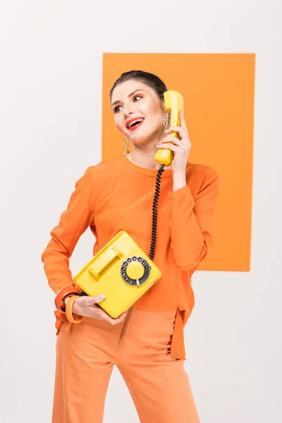 Fashionable smiling woman talking on retro telephone and posing with turmeric on background — Stock Photo