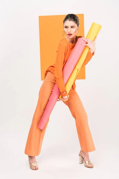 Stylish young woman holding paper rolls, looking away and posing with turmeric on background — Stock Photo