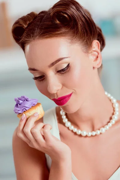Mulher pin up bonita no colar de pérolas segurando cupcake caseiro — Fotografia de Stock