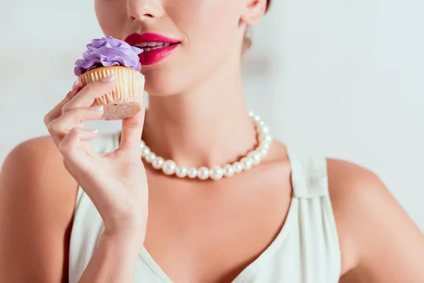 Vista parziale di pin up ragazza degustazione cupcake fatti in casa con crema viola — Foto stock