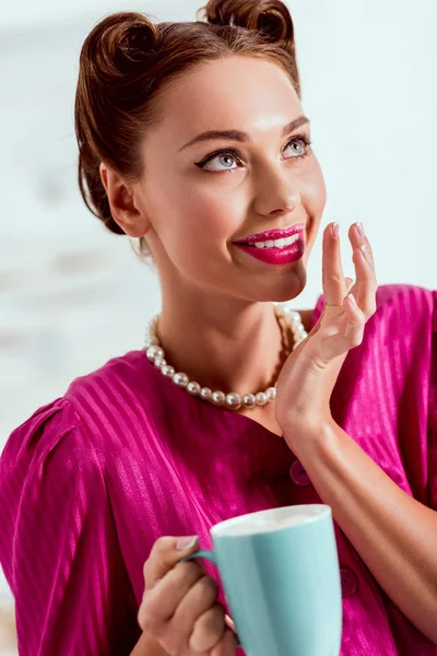 Hermosa chica pin up con taza de café sosteniendo la mano cerca de los labios - foto de stock