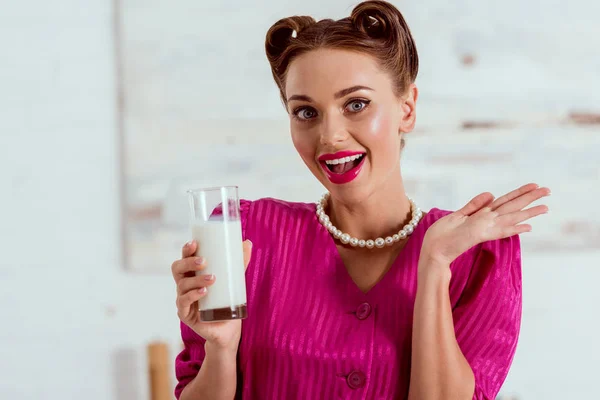 Hermosa chica pin up sosteniendo vaso de leche y saludando la mano - foto de stock
