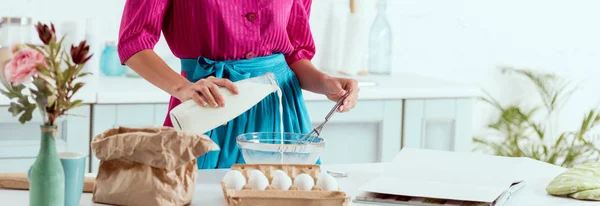 Cropped view of pin up girl adding milk from bottle to the ingredients for making dough — Stock Photo